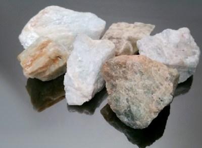 Seis pedras brancas e bege com texturas rugosas em superfície escura