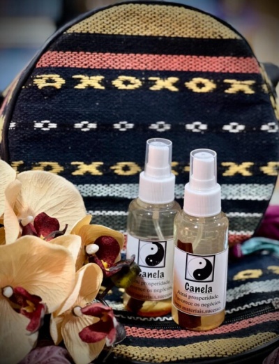Dois frascos de spray Canela com etiqueta yin-yang sobre tecido colorido e flores artificiais