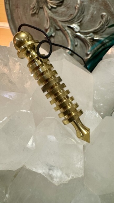 Pêndulo dourado em fio preto sobre cristais transparentes