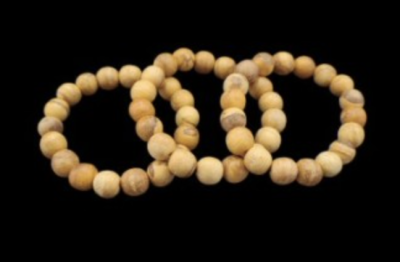 Três pulseiras de contas de madeira clara sobre fundo preto