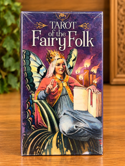 Caixa de tarot com ilustração de fada com asas e coroa segurando um livro.