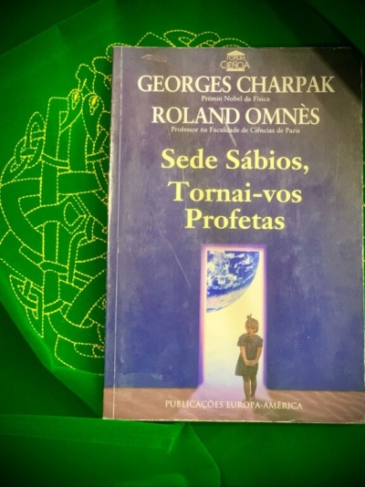 Livro com capa azul escuro e texto amarelo sobre fundo verde bordado