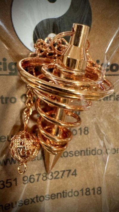 Pêndulo dourado em espiral com esfera trabalhada sobre papel com texto