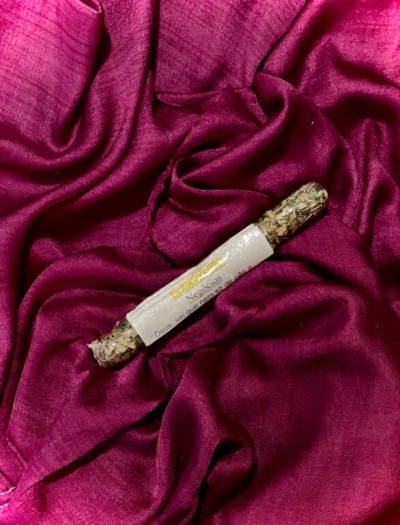 Incenso com embalagem em papel branco sobre tecido rosa escuro brilhante e enrugado