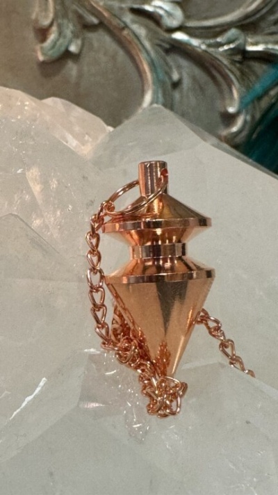 Pêndulo dourado com corrente sobre superfície de cristal