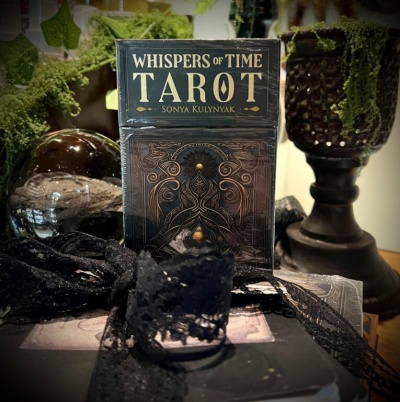 Baralho de cartas de tarot Whispers of Time na caixa preta com decoração detalhada e tecido de renda preta á frente.
