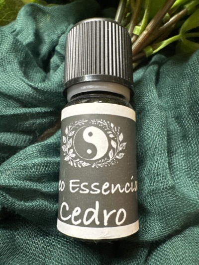 Frasco de óleo essencial Cedro com rótulo cinza e branco sobre tecido verde