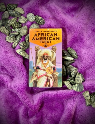 Caixa de baralho de tarot African American Tarot sobre tecido violeta com pedras escuras