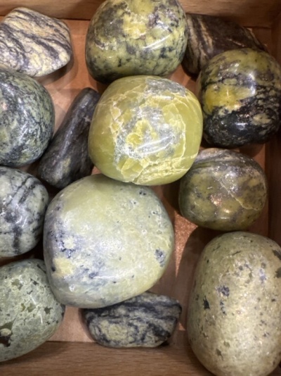 Pedras polidas verdes, amarelas e cinzentas numa caixa de madeira