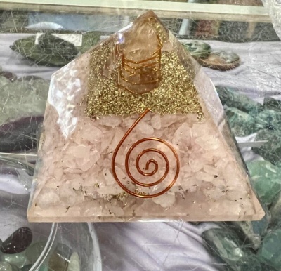 Pirâmide decorativa de resina com pedras rosas, detalhes dourados e fio de cobre em espiral.