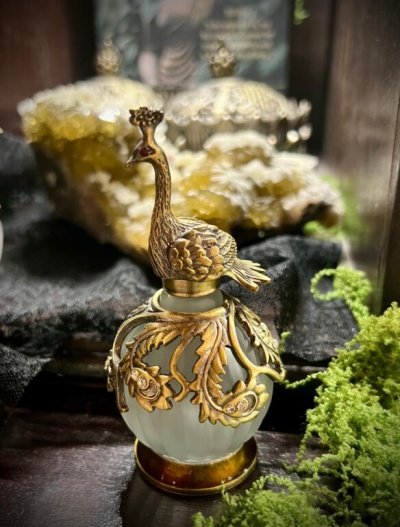 Frasco decorativo de vidro com tampa dourada em forma de pavão e ornamentos