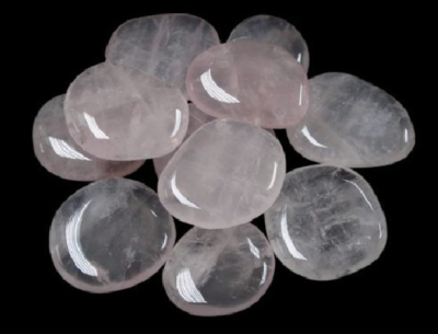 Pedras polidas de quartzo rosa em fundo preto