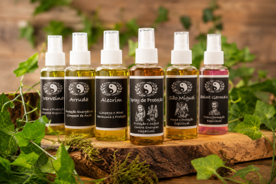 Frascos de spray com rótulos pretos e líquido colorido, em base de madeira com folhas verdes
