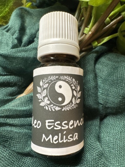 Frasco de óleo essencial Melisa com símbolo yin-yang e flores sobre tecido verde