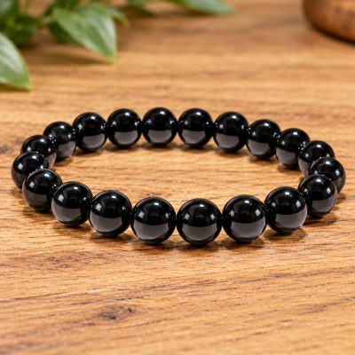 Pulseira de contas pretas brilhantes sobre mesa de madeira.