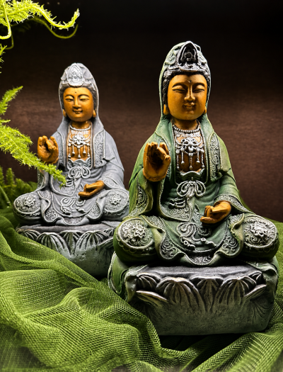 Esculturas decorativas em verde e cinza com detalhes laranja sentadas sobre bases ornamentadas.