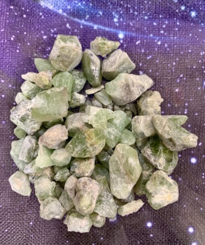 Pedaços brutos de pedras verdes sobre fundo roxo estrelado
