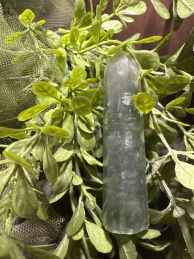 Pedra verde polida sobre folhas verdes artificiais