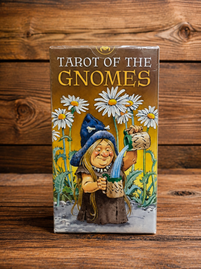 Caixa de Tarot of the Gnomes com ilustração de gnomo e flores sobre mesa de madeira