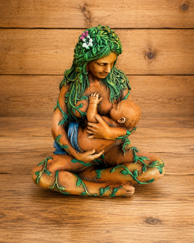 Escultura de mulher a amamentar um bebé, com folhas verdes no corpo e cabelo.