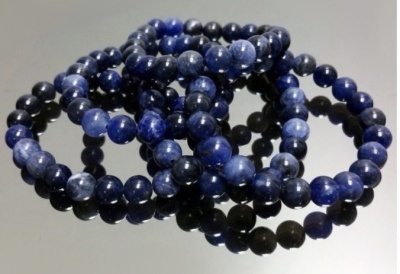 Pulseiras de contas azuis esféricas sobre superfície preta refletora