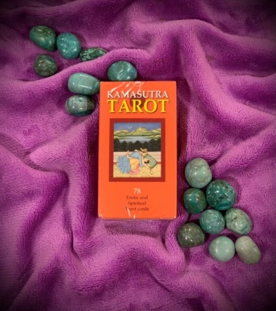 Caixa vermelha de cartas Kamasutra Tarot com pedras verdes sobre tecido roxo