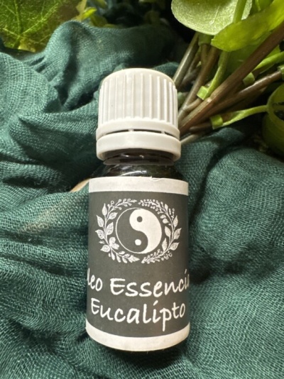 Frasco pequeno de óleo essencial de eucalipto com rolha branca e rótulo cinzento sobre tecido verde