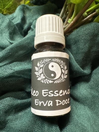 Frasco pequeno de óleo essencial de Erva Doce com rótulo preto e símbolo yin-yang sobre tecido verde.