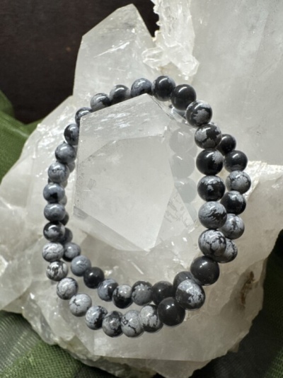 Pulseira de bolas pretas e brancas sobre cristal translúcido com fundo verde