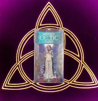 Baralho de tarot Universal Celtic Tarot com figura feminina, padrão celta amarelo sobre fundo roxo.