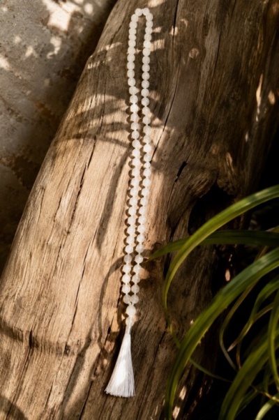 Colar de contas brancas com tassel sobre madeira rústica