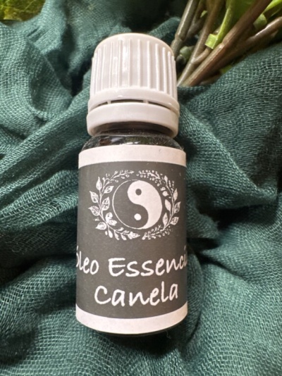 Frasco de óleo essencial de canela com etiqueta preta e símbolo yin-yang sobre tecido verde