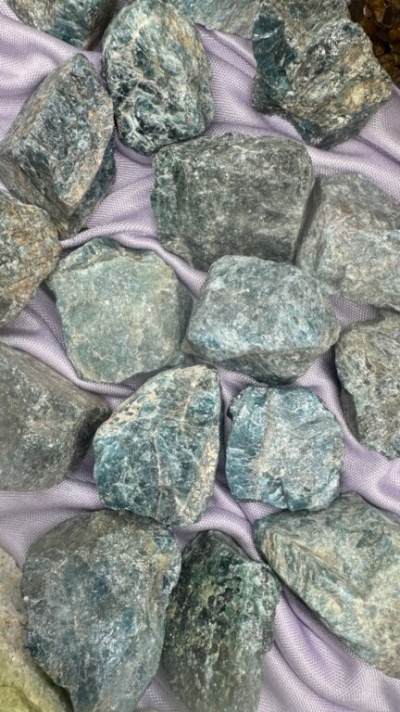 Pedras brutas verdes e cinzentas sobre tecido violeta claro