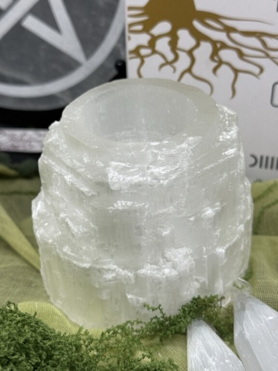 Vela de selenite branca translúcida com musgo verde e cristais brancos