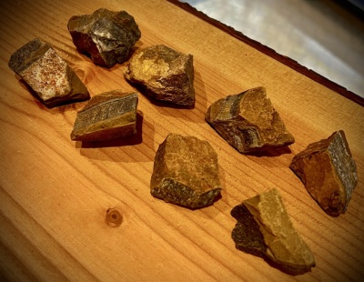 Pedaços de pedra castanhos e cinzentos sobre mesa de madeira clara