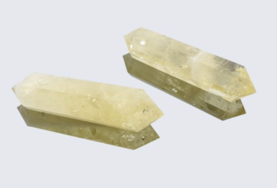 Dois cristais amarelo transparente alongados com pontas facetadas sobre fundo branco