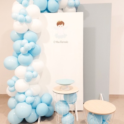 Decoração para batizado com balões azuis e brancos, estrutura com anjo e mesas com balões azuis.