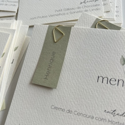 Tarjetas de papel branco texturizado com texto cinzento e preto e clips dourados triangulares