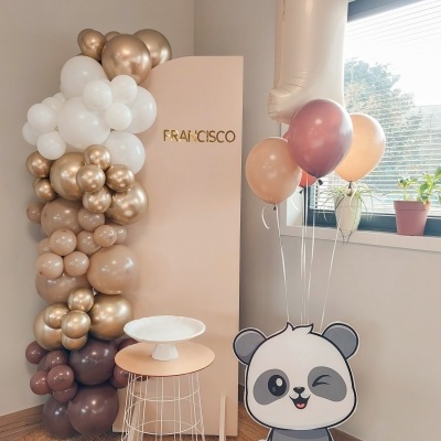 Decoração de festa infantil com balões de várias cores, painel com nome, mesa alta e balão panda em interior luminoso