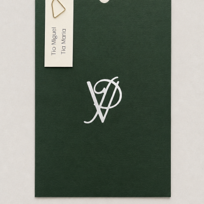 Envelope verde escuro com monograma branco e cartão creme com nomes