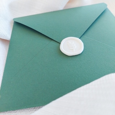 Envelope verde com selo branco sobre tecido branco
