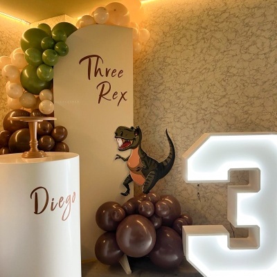 Decoração de festa com balões, painel branco, dinossauro e número 3 iluminado