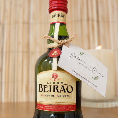 Garrafas de Licor Beirão com cartão branco amarrado e vela acesa ao fundo