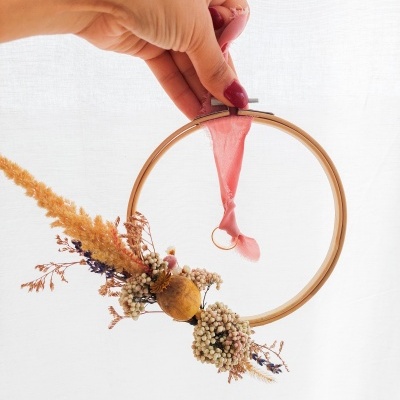 Aro decorativo de madeira com flores secas e fita cor-de-rosa