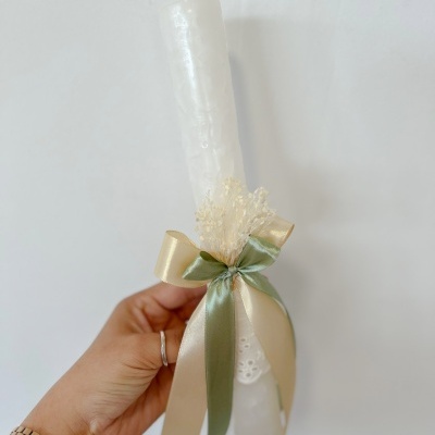 Vela branca com laço dourado e verde e ramos secos