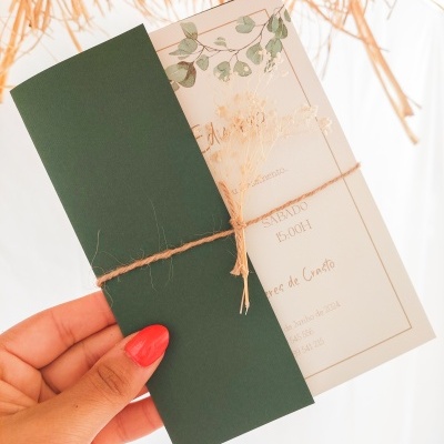Convite de casamento com envelope verde escuro e cartão branco com decoração de folhas verdes e texto amarrado com cordão de sisal
