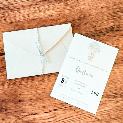 convite branco com envelope branco e cordão azul sobre madeira clara
