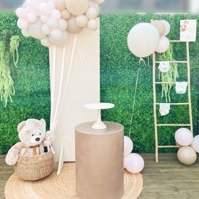 Decoração de festa com balões pastel, cilindro bege, urso de peluche e escada decorativa