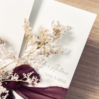 Convite branco com laço roxo e ramos secos decorativos