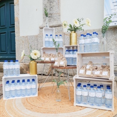 Mesa com caixas de água engarrafada e pacotes em sacos de papel decorada com flores amarelas